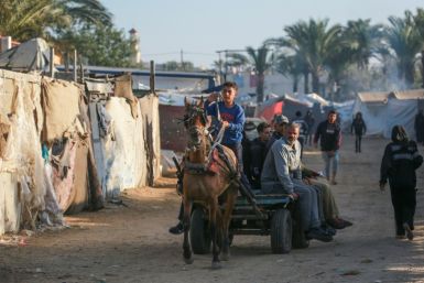 Displaced Palestinians using animal-drawn carts pass flimsy shelters in Al-Zawayda, central Gaza