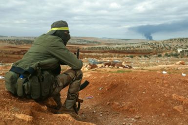 A fighter from Hayat Tahrir al-Sham (HTS) mans a position in the eastern outskirts of Atarib town, in Syria's Aleppo province, as smoke rises in the distance during clashes with the Syrian army