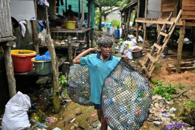 A fisherman at his village on Thailand's southern island of Koh Chang carries bags of plastic waste to sell
