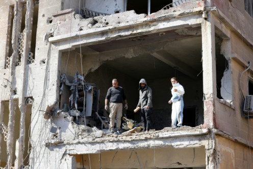 Returning residents assess the damage to an apartment in a block heavily damaged by an Israeli air strike.