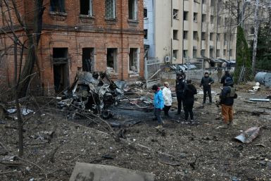 Ukrainian law enforcement officers and local residents stand among debris in the courtyard of a damaged residential building following a missile attack in Kharkiv